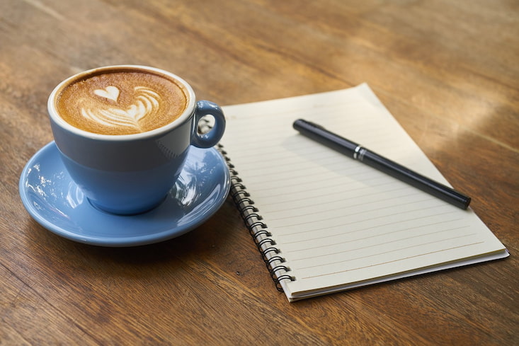 テーブルに置かれたノートとコーヒー