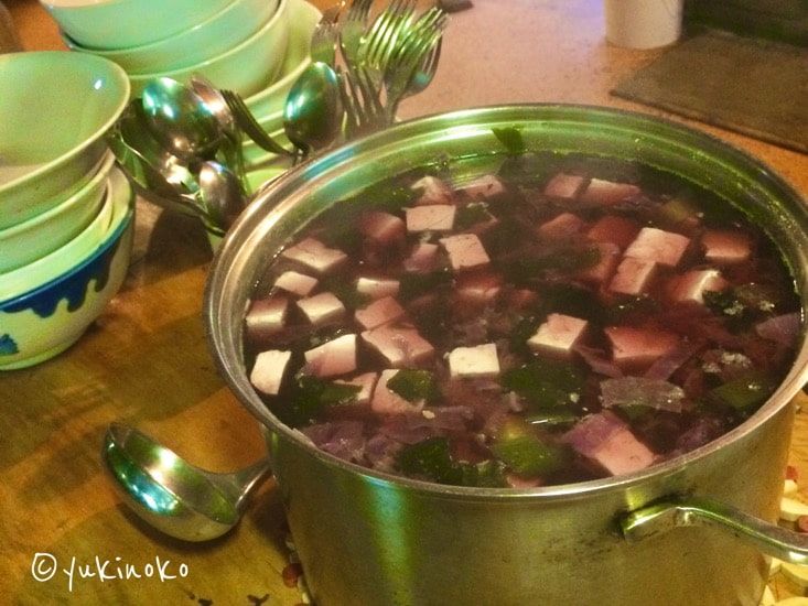 手前の１０L程の鍋に入っているのは、お汁は紫色で具はわかめと豆腐と紫キャベツの味噌汁で、奥に10枚ほどの器とスプーンとフォークが置いてある