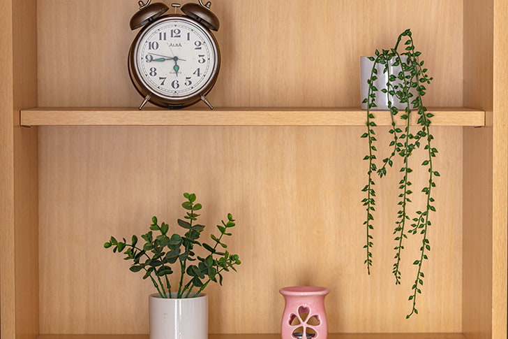 木の棚に並べられている時計と植物と陶器の器