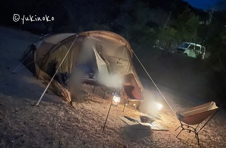 夜のキャンプ場の芝生の上にogawaのシャンティRと椅子2つ、テーブルなどが置いてある様子。正面から見て左サイドから見たもの。車なしの写真。
