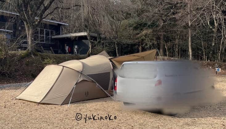 ogawaテント・シャンティRがキャンプ場の芝生の上で設営され、キャノピー部分を広げてタープのようにしている様子を後ろから見て右サイドの後ろから撮影したもの