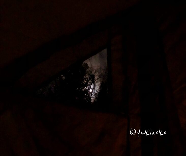 テントの隙間から夜空が見えて月と雲が見えているが、テントは暗くてほぼ見えない