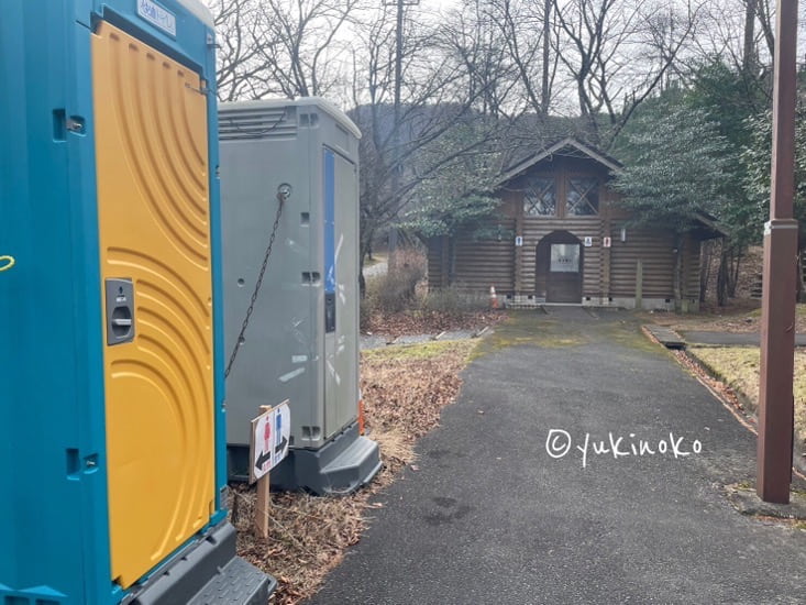 手前に仮設トイレが二つ、奥の木製の建物は冬季使用禁止のトイレ