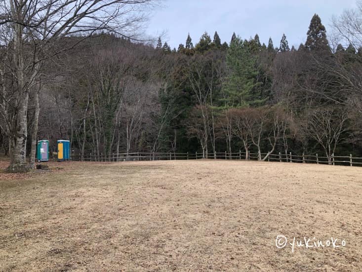 芝生の広場が広がっていて左奥には仮設トイレが2つ小さく見える