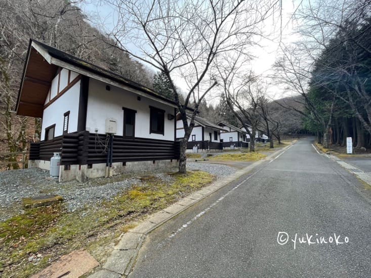 中央に奥側へ延びる道路、左にキャンプ場のコテージが5棟並んでいる