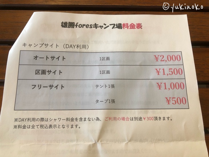 キャンプ場の料金表が記載された用紙が中央に大きく写っている