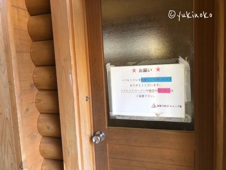 木でできた建物のドアがアップで写っていて、ドアのガラス部分に張り紙が貼ってある