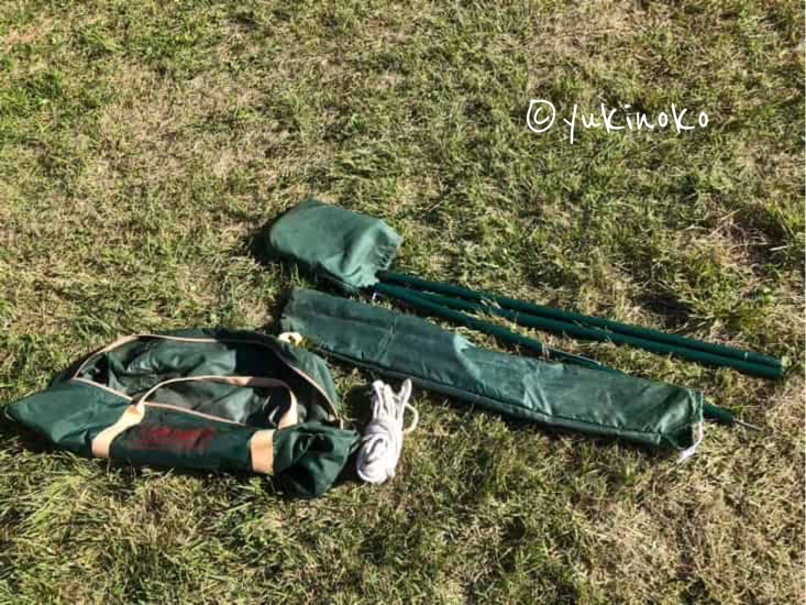 芝生の上に、タープが入っていた袋とポールが入っていた袋と一緒に、ポールが一つと結ばれたロープが置いてある