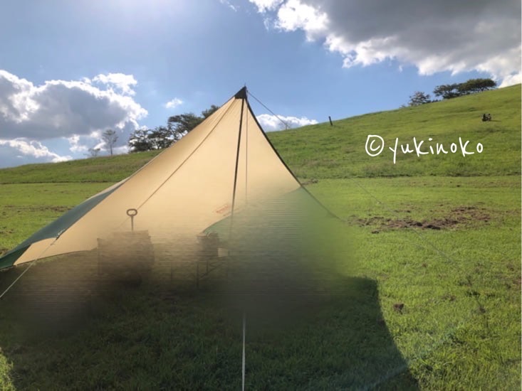 タープを張り終わったところ、青空と緑の丘を背景に、タープがピンと張ってある