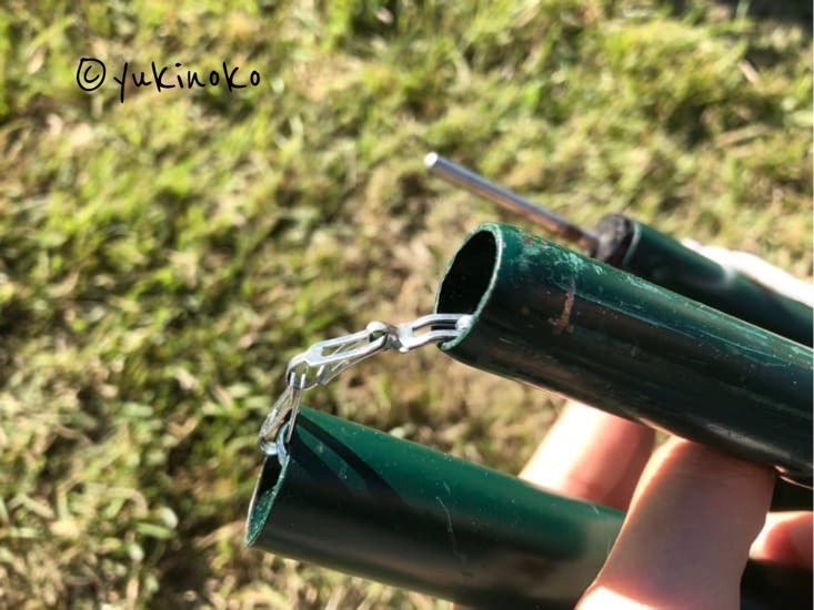芝生の上で、タープのポールの中に入っている金属の鎖のような物が見えている