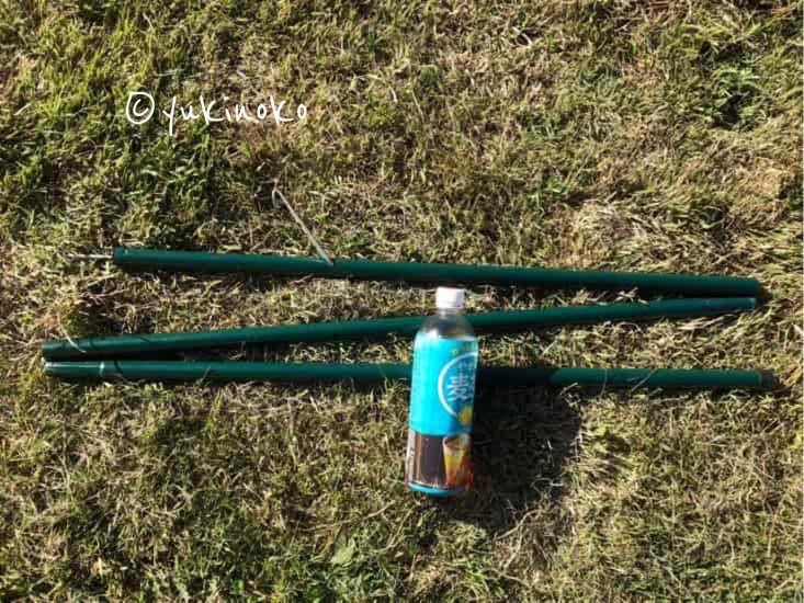 芝生の上にタープポール一本と500mlのペットボトルが置いてある