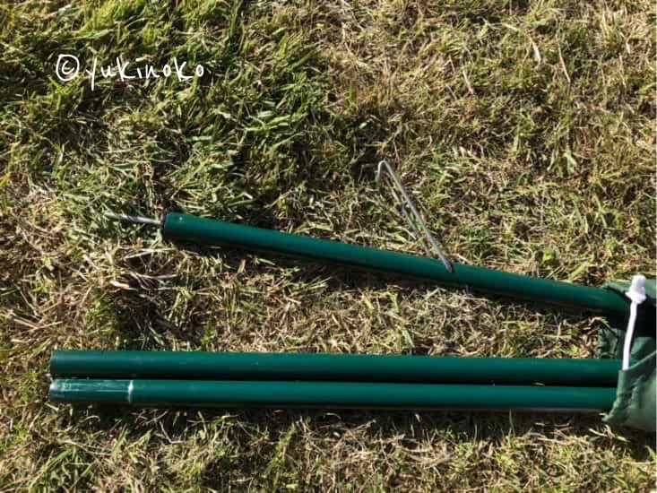 芝生の上に、タープポールが袋から半分出た状態で置いてある