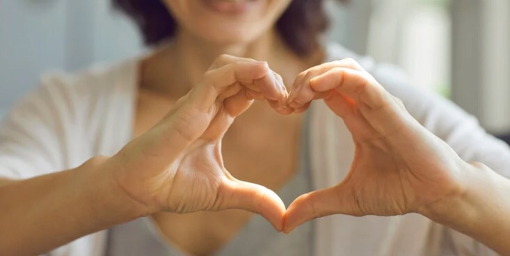 両手でハートを作ってこちらに向けている人が1人写ってる