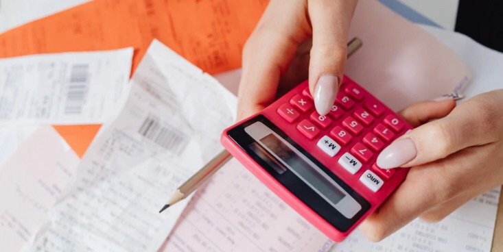 テーブルの上にレシートがいくつか置いてあり、両手で電卓を持っている