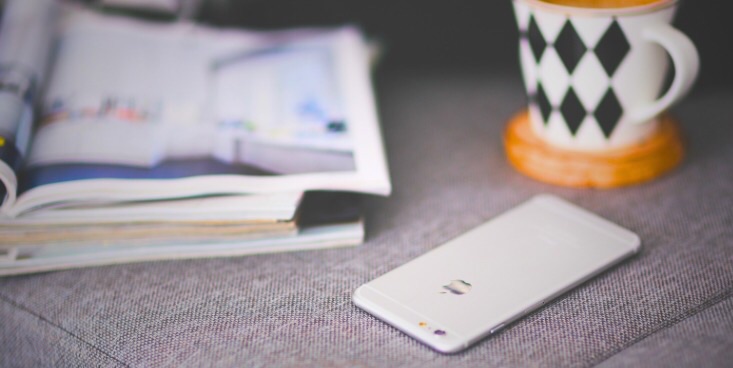 左奥に雑誌、右奥にマグカップ、手前に携帯が置いてある