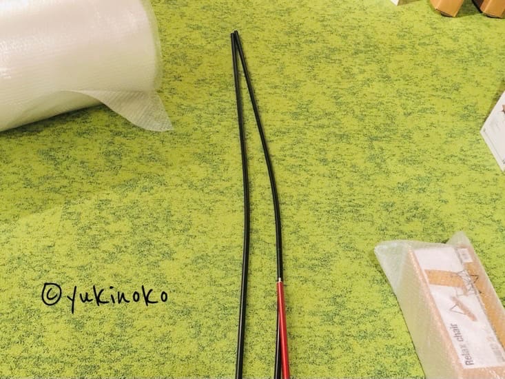 ポール2本が床に置いてあり、先端部分が真っ直ぐではなく少し歪んで曲がっている